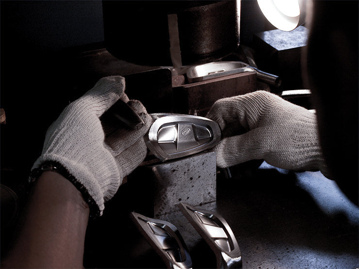 Craftsman carefully assembling a metal automotive part, showcasing precision and skilled craftsmanship.