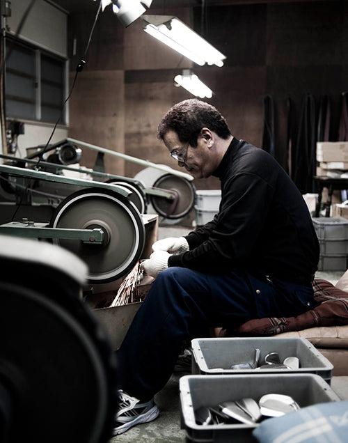 Craftsman working with tools in a workshop, focused on metal polishing and fabrication processes.